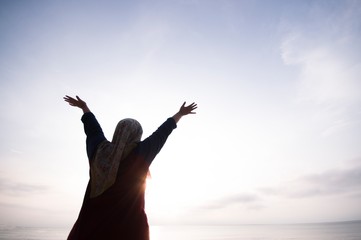 Unidentified silhouette happiness and joyful woman girl rise hand up during oceanview on blue sky background - Image