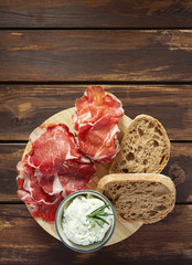 coppa di parma meat, cream cheese and ciabatta bread on wooden surface