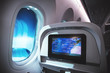 Airplane interior with seats, window inside an aircraft and multimedia screen displayed destination.