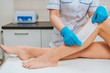 Partial view of cosmetologist in rubber gloves doing leg wax depilation