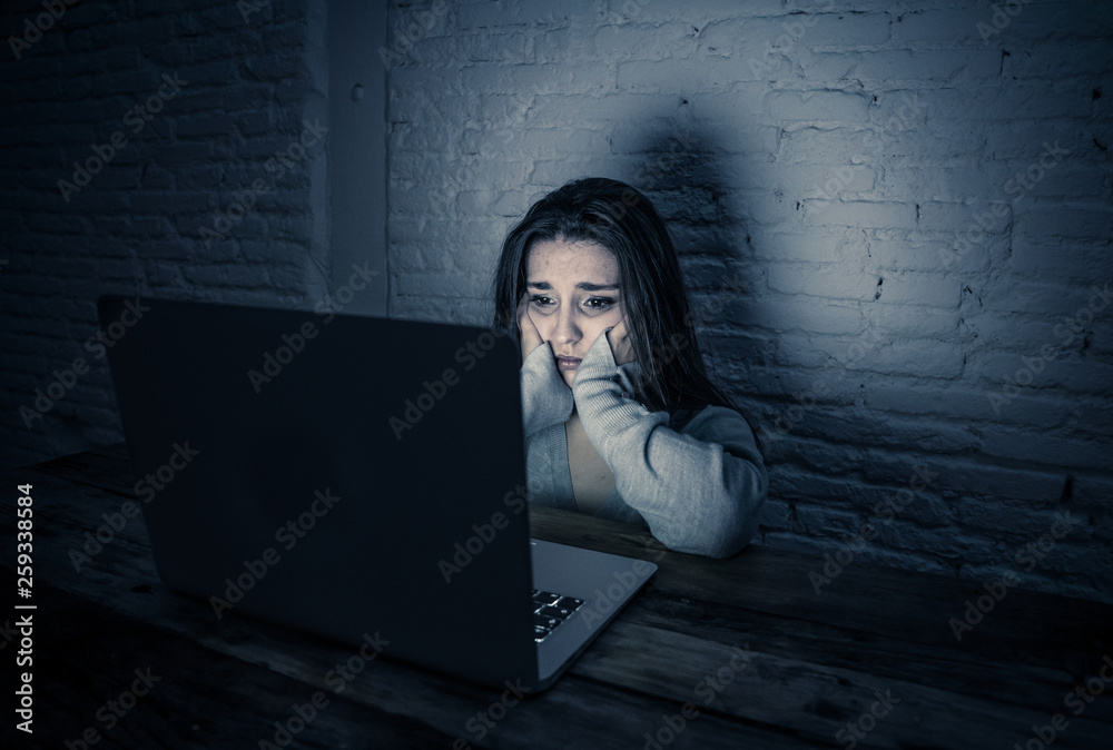 Scared woman on laptop in the dark feeling fear suffering online ...