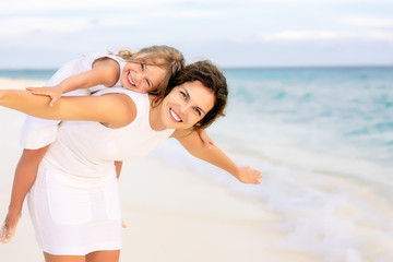 portrait of happy mother and little daughter on sunny beach on maldives at summer vacation