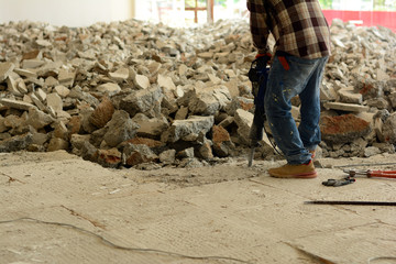 the  worker using dismantling machine hitting into the concrete  ground