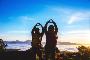 Lover women and men asians travel relax in the holiday. Stand up for sunrise on the Moutain,happy honeymoon,Raised his hand to make a heart shape.