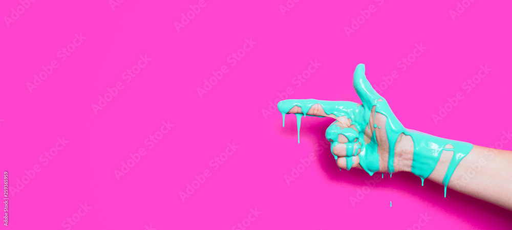 female hand in the paint flowing down the finger shows the direction on a colored background, creative idea of advertising, a gesture of clicking - obrazy, fototapety, plakaty 