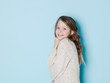 © epiximages - pretty and cool 9 year old girl with brown wool sweater posing in front of blue background