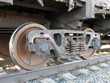 The railway carriage springs and wheels on reils close-up