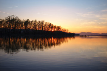 Poster - Sunset in strong colors over a river with reflections of trees