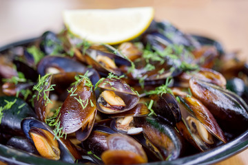 Cooked mussels with greens on a plate, seafood, soft focus