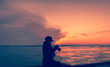© shchus - Silhouette girl photographer in the winter at sunset. A single woman takes pictures against the sky and clouds. Tourism and creativity. Copy space and picture.