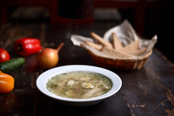 Wall Mural - chicken soup with quail eggs in a white plate on a wooden background