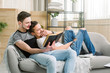 © sofiko14 - Attractive gay couple reading book on the sofa at home in living room