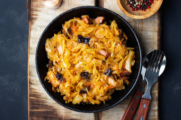 Wall Mural - Traditional dish of polish cuisine - Bigos from fresh cabbage, meat and prunes. Top view. Dark background.