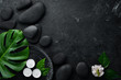 Zen stones and leaves with water drops. Spa background with spa accessories on a dark background. Top view. Free space for your text.