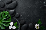 Zen stones and leaves with water drops. Spa background with spa accessories on a dark background. Top view. Free space for your text.