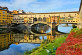 View of the historic Ponte Vecchio with reflections in the Arno river during autumn, Florence, Tuscany, Italy