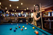 © RomanR - Beautiful woman in black dress posing with billiard cue