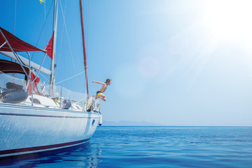 Boy jump in sea of sailing yacht on summer cruise. Travel adventure, yachting with child on vacation.