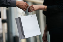 Man Giving Gift In Paper Bag To Woman, Close-up