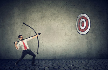 business man trying to hit a target his goal with bow and arrow