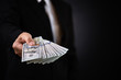 © Siam - Businessman with money in hand and giving money as a bribe, US dollar (USD) bills - investment, success and profitable business concepts.