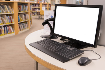computer with blank screen monitor on table in interior library
