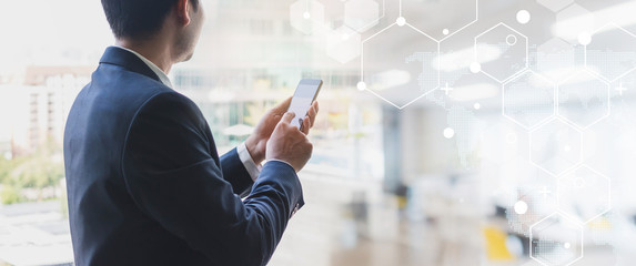 Success business man using smart phone on window with city building background and futuristic technology connection.Concept of business people use technology.