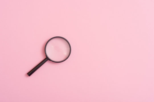 Magnifying glass on pink background. Top view. Flat lay. Copy space. Concept