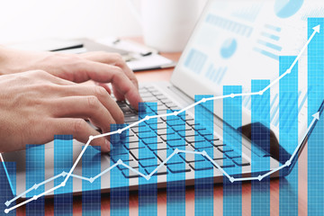 Business growth planning. Businessman analyzing data and preparing reports.Laptop and growth graphs.