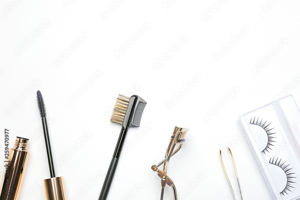 Mascara with false eyelashes and tools on white background