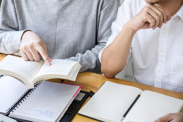 Wall Mural - high school tutor or college student group sitting at desk in library studying and reading, doing ho