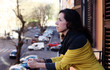 © dubova - beautiful mature woman standing on the balcony looking to the street