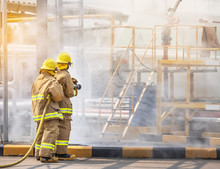 Professional Firemans Brave Buddy Team Assistance In Yellow Fire Fighter Uniform Holding Fire Hose Nozzle Fighting With Fire Flame In The Industrial Factory