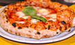 typical Neapolitan-style Italian pizza with a high and soft edge, mozzarella tomato and basil