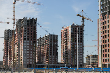 Construction of a multi-storey residential complex. Crane near the building under construction. Background construction site.