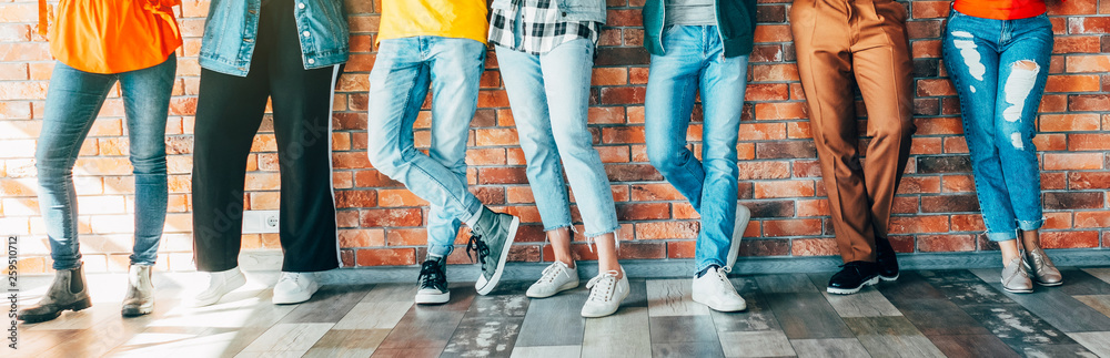Millennials community. Cropped shot of young people in casual outfits standing against brick wall, socializing during break. - obrazy, fototapety, plakaty 