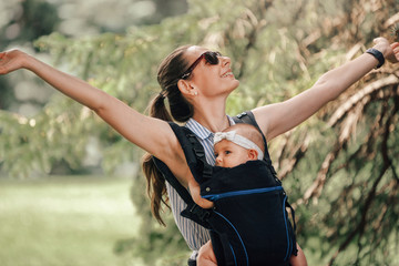 Little baby girl and her mother walking outside babywearing in the ergo carrier concept