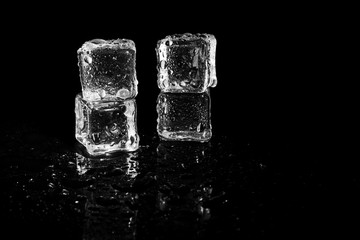 ice cubes reflection on black table background.