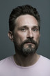 © Augustino - Fabulous at any age. Portrait of 40-year-old man standing over dark gray background. Close up. Classic style. Scar on forehead. Studio shot