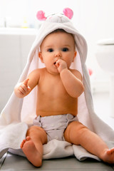 A baby girl covered with a bath towel in the bathroom