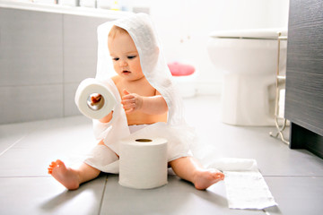 Toddler ripping up toilet paper in bathroom