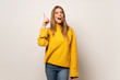 © luismolinero - Woman with yellow sweater over isolated wall intending to realizes the solution while lifting a finger up