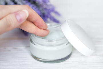 Cosmetic cream container on white wooden background with flowers. Face cream