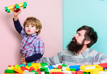 Father son game. Father and son create constructions. Bearded man and son play together. Every dad and son must do together. Dad and kid build plastic blocks. Child care development. Family leisure