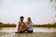 Loving Couple Sitting On The Pier On Lake
