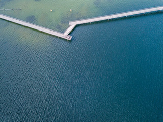 Wall Mural - Aerial view of pedestrian bridge over lake. Narrow wooden bridge with beautiful seafloor and reflection