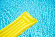 Beach summer holiday background. Inflatable air mattress on swimming pool water. Yellow lilo and summertime accessories on poolside. Top view and copy space. Banner