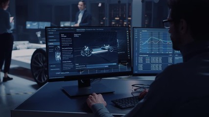 Fototapete - Professional Engineer Works on a Computer with a 3D CAD Software and Tests the Electric Car Chassis Prototype with Wheels, Batteries and Engine Standing in a High Tech Development Laboratory.