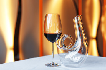 glass of wine and a decanter on a table with a white tablecloth.