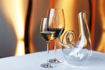 glass of wine and a decanter on a table with a white tablecloth.